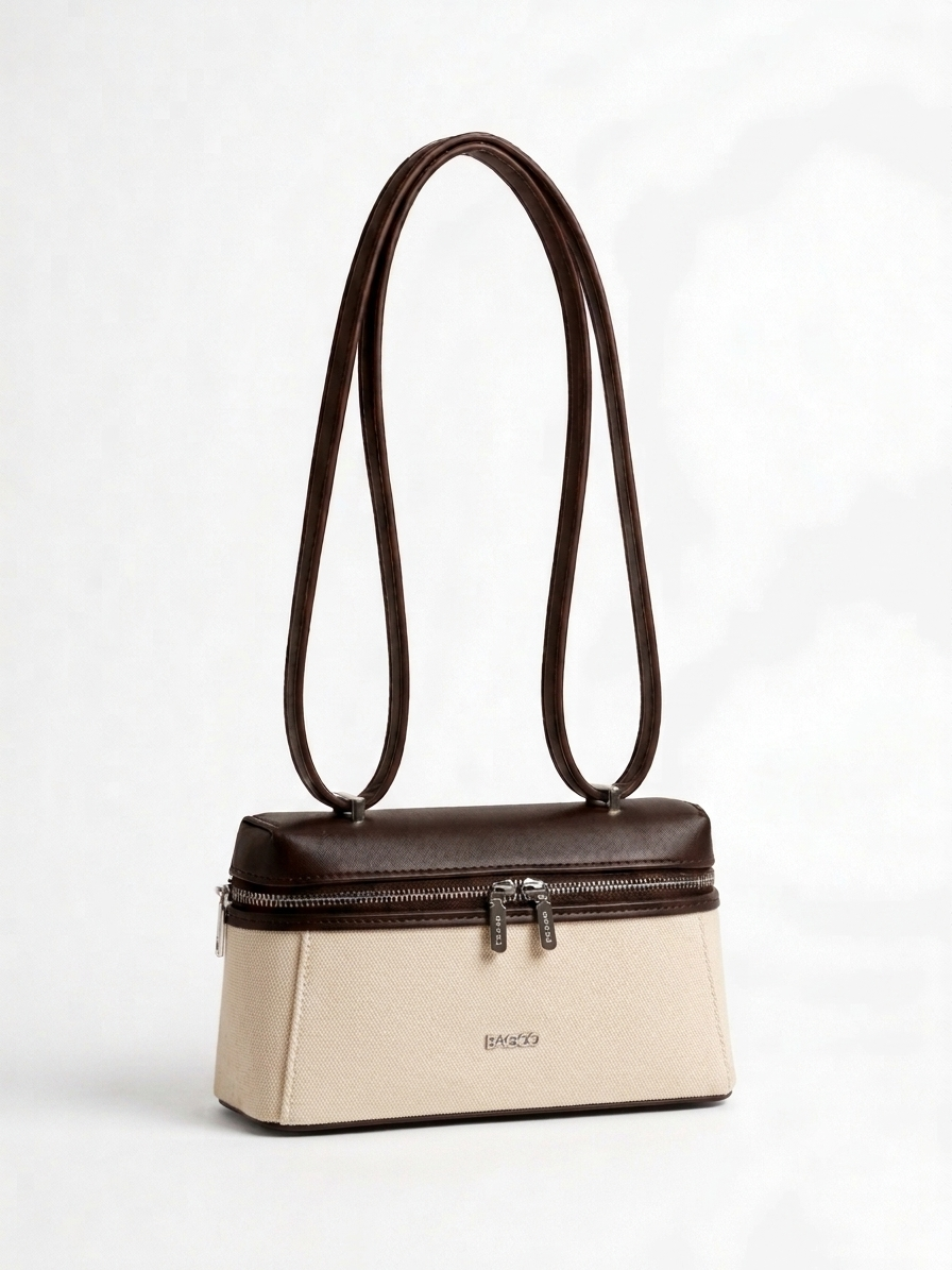 Sac à main structuré bicolore beige et marron foncé, avec longues anses fines, fermeture zippée sur le dessus et design élégant minimaliste.