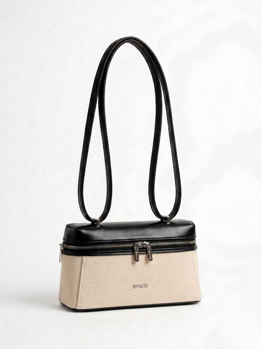 Sac à main structuré bicolore beige et noir, avec longues anses fines, fermeture zippée sur le dessus et design élégant minimaliste.
