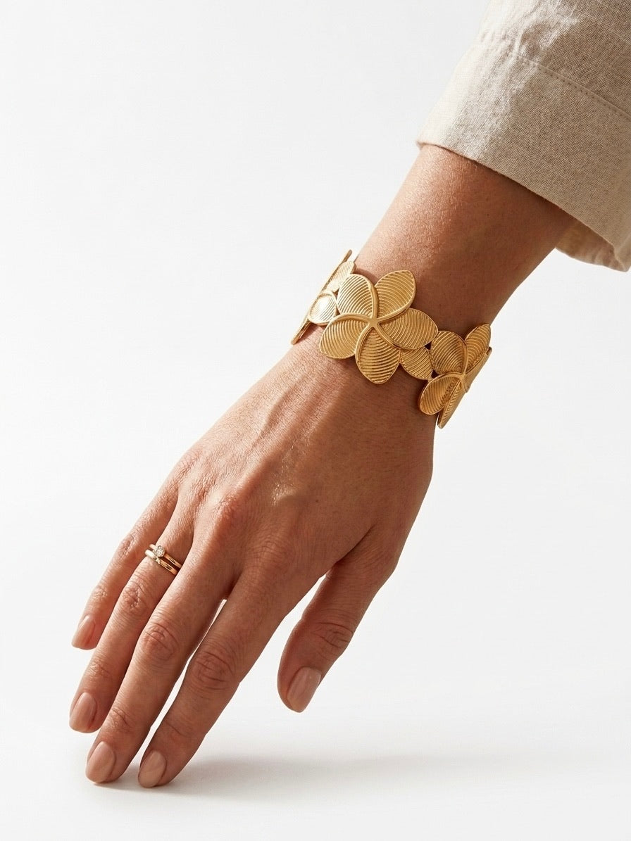 bracelet manchette doré à motifs de fleurs texturées porté au poignet
