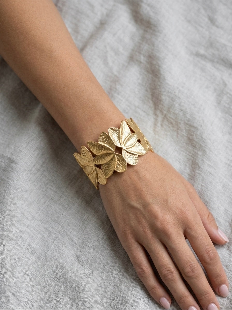 bracelet manchette doré texturé en acier inoxydable à motifs de fleurs de lotus porté au poignet