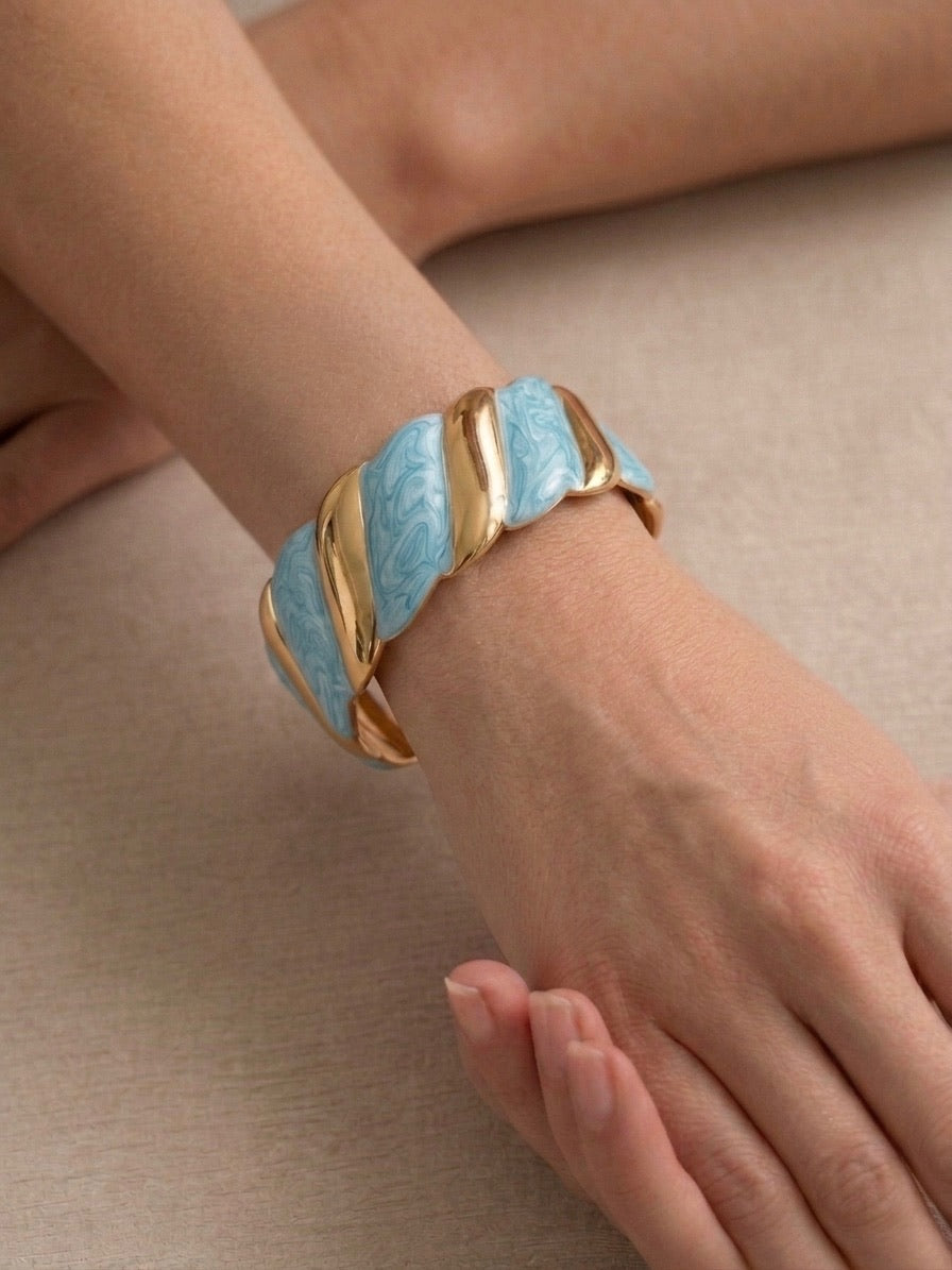 bracelet manchette torsadé en métal doré et maillons effet nacre bleu porté au poignet