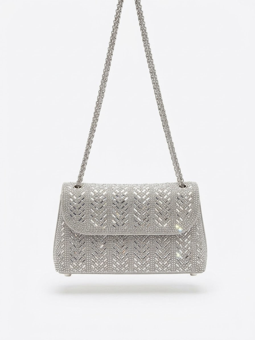 Sac à main argenté à strass avec motif géométrique et chaîne tressée.